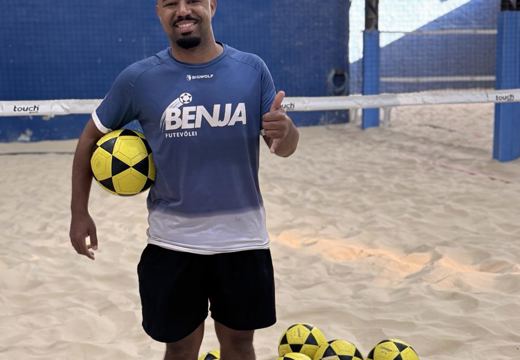 Professor Alyson na quadra de areia do Benja, com bolas e rede para as aulas de futevôlei.