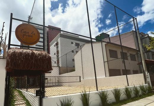 Entrada da Casa e quadra de areia ao ar livre, cercada por redes de proteção.